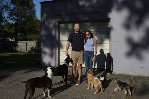 Kim Bode and Josh Byler pose outside. They are surrounded by dogs. 