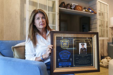 Katie Kerstetter is sitting in a living room. She is holding up a framed picture.