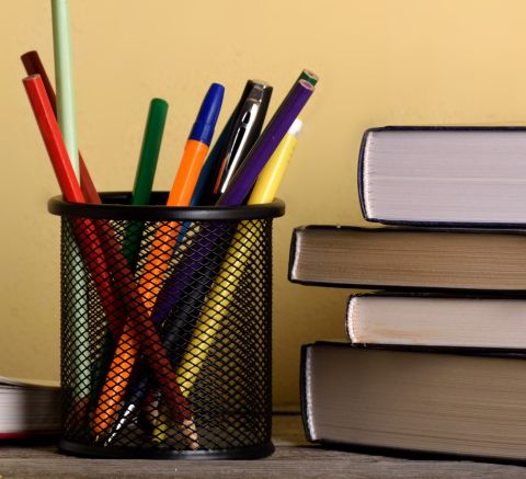stock image of books and a cup filled with pens in a classroom