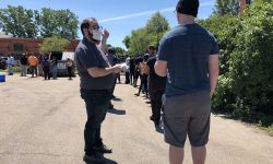 Jack Crawley of General Motors hands out codes for Flint Assembly job seekers to start their applications with their phones while they waited in line at a hiring event on June 17. 