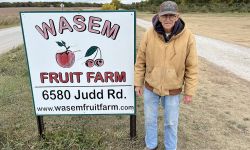 older man by sign on side of the road