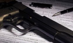 gun with bullets sat on top of paperwork