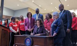 whitmer sitting at a desk with people surrounding her