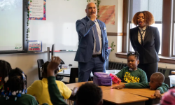 Two teachers stand in classroom in front of students