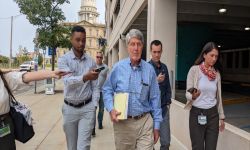 Gerald Clixby walks with reporters holding phones