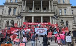 people with signs that says "rent is too damn high" in front of the capitol