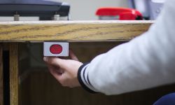 A hand ready to press a panic button under an administrative desk