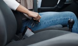 woman driver fastening seat belt in auto