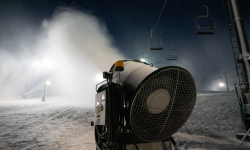 A snow gun blows fake snow onto a mountain.