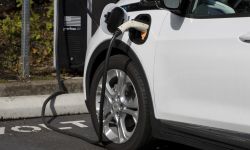 A Chevy Bolt EV electric car is seen charging at a public charging station in a parking lo
