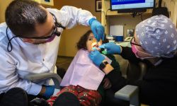 Young girl sits in dental chair with a dentist