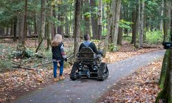 Two people, one in a wheelchair, on a trail.