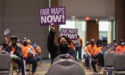people holding signs that says "Fair Maps Now"