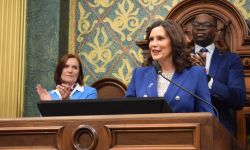 Michigan Governor Gretchen Whitmer stands at a podium during a State of the State address 