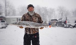 man holding a big fish in the snow