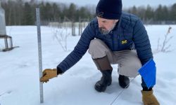 man sticking ruler into snow