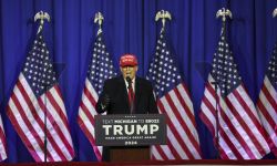 Donald Trump speaks at a podium with American flags behind him.