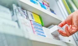 Closeup pharmacist hand holding medicine box in pharmacy drugstore.