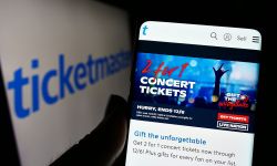 Person holding smartphone with webpage of US company Ticketmaster Entertainment Inc. on screen in front of logo. 