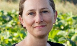 Jen Schaap headshot, with a farm in the background