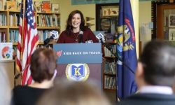 Gov. Gretchen Whitmer at a podium with bookshelves behind her