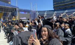 A bunch of students in black graduation room. They are sitting in seats