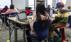 Children are working at their desks in a classroom. 