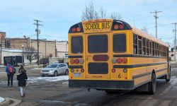 Kids walking away from the school bus. There's snow on the ground