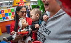 Flint pediatrician Dr. Mona Hanna with babies. She is wearing a birthday hat. 
