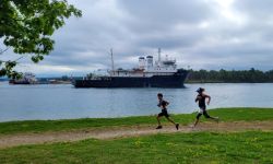 Runners race past a freighter