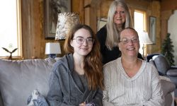 Family poses for a picture. They are sitting on the couch.