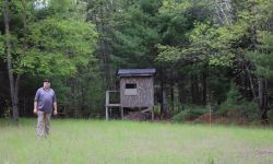 A man stands in a food plot next to a deer blind in northern Michigan