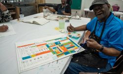 Ray Smith sits at a table while he paints. 