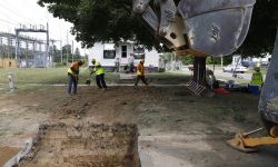 Workers work to fill a hole in front of a home in Flint, Michigan.