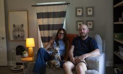 Kim Bode and Josh Byler pose together on a couch with their dogs.