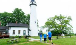 Two people walk toward a lighthouse