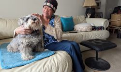 Tonya McCoy sits with a dog on a couch. 