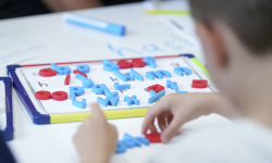 A view of a child from the back.  The student is participating in an activity that focuses on practicing letters. 