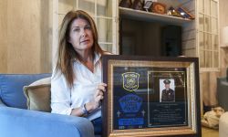 Katie Kerstetter is sitting in a living room. She is holding up a framed picture.