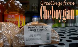 A postcard that says "Greetings From Cheboygan" with a picture of Mackinac Island fudge