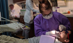 dental hygienist looks into child's mouth