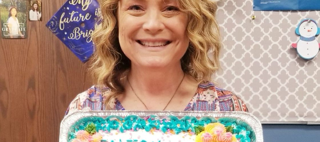 Susy Talentino holding up cake that says "happy retirement susy"