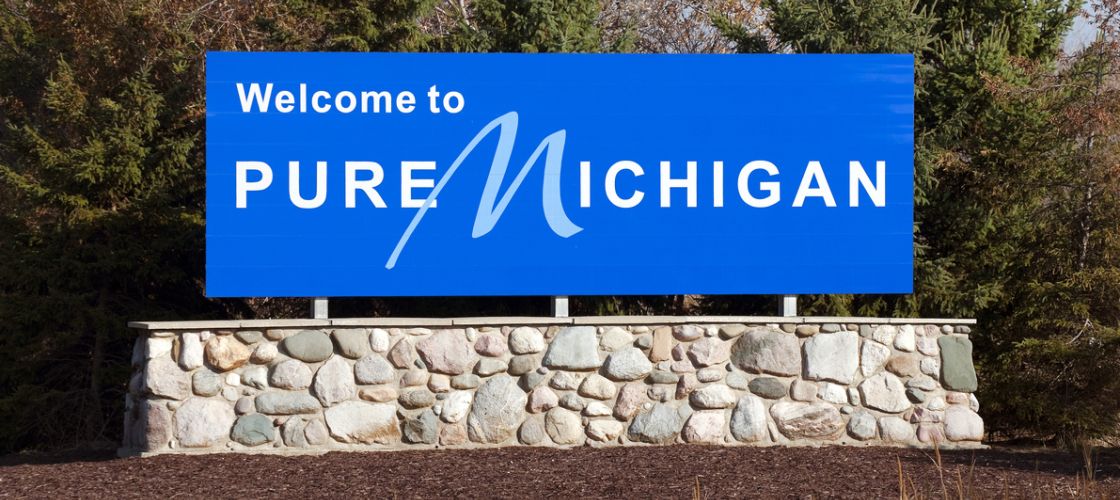 Blue welcome to pure michigan sign on a stone wall 