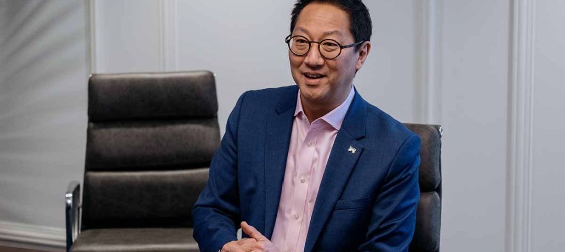 Santa Ono sits at a table. 