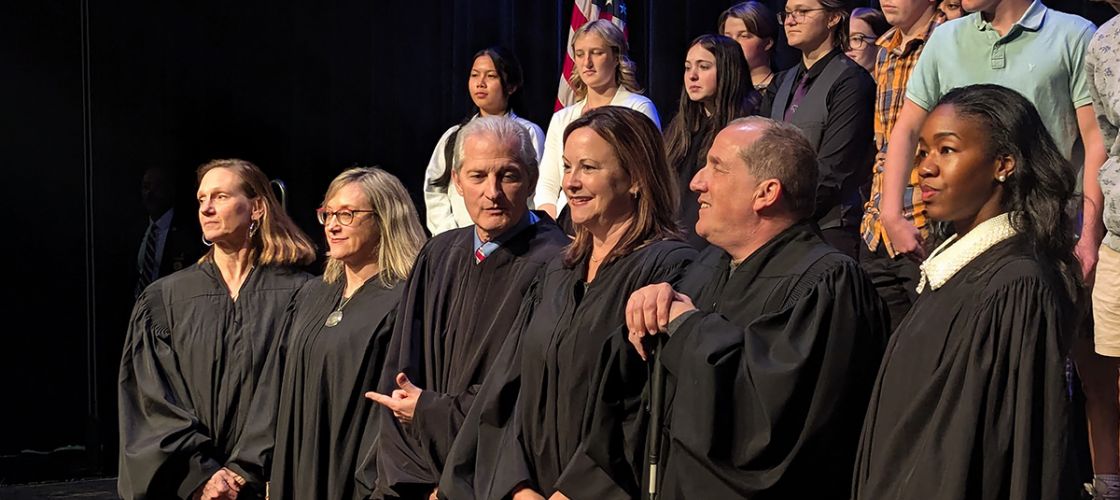 Michigan Supreme Court justices stand in a row. Students are behind them.