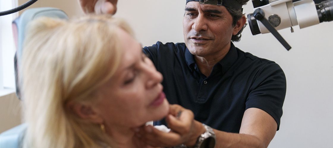 Dr. Bobby Mukkamala sees a woman patient in a medical office.