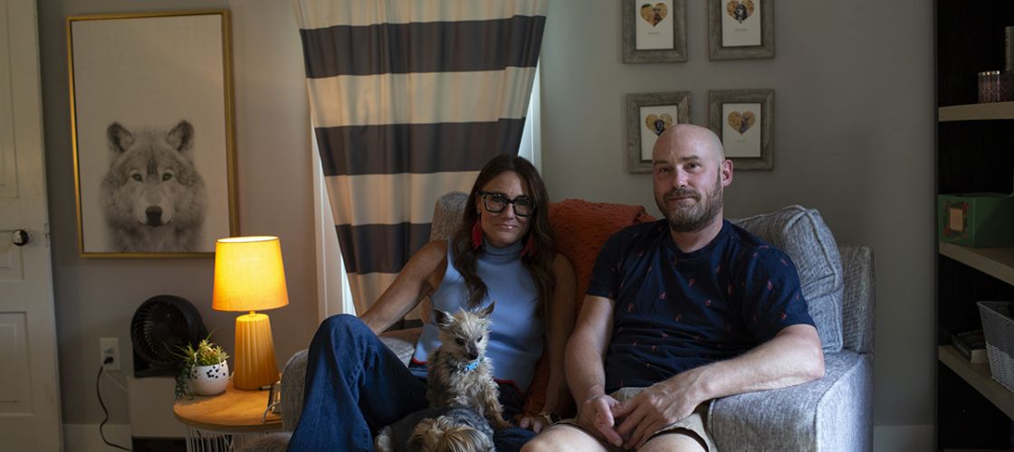 Kim Bode and Josh Byler pose together on a couch with their dogs.