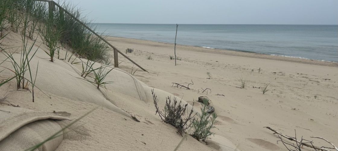 A sandy dune is seen in the foreground with Lake Michigan beyond