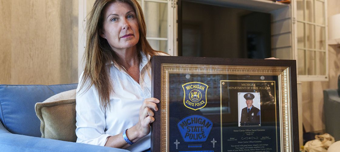 Katie Kerstetter is sitting in a living room. She is holding up a framed picture.
